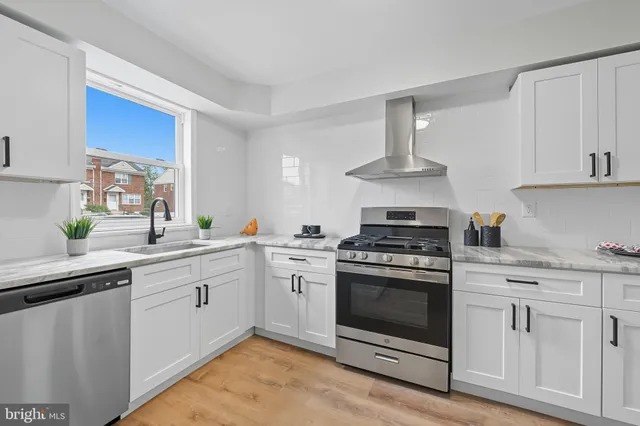 a kitchen with stainless steel appliances granite countertop a stove and white cabinets