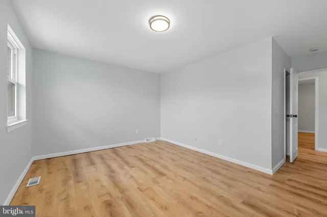 an empty room with wooden floor and window