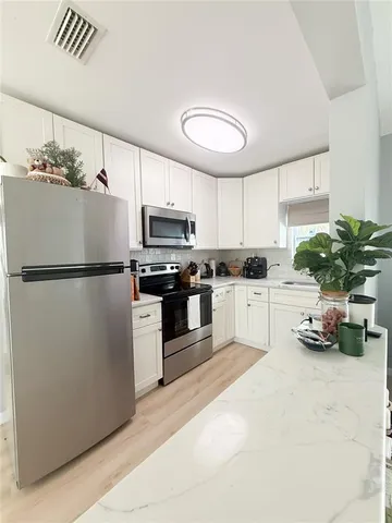 a kitchen with kitchen island a counter space stainless steel appliances and cabinets