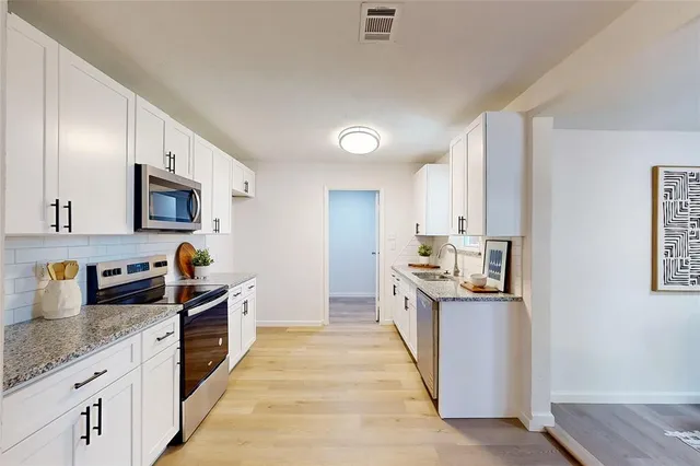 a kitchen with stainless steel appliances granite countertop a sink a stove and a wooden floors