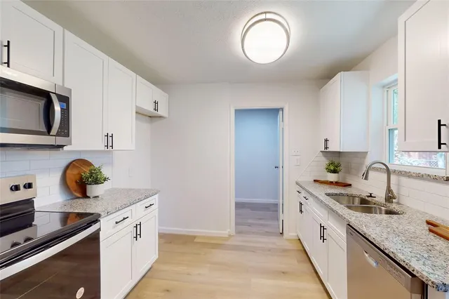 a kitchen with stainless steel appliances granite countertop a stove top oven a sink dishwasher a dining table and chairs with wooden floor