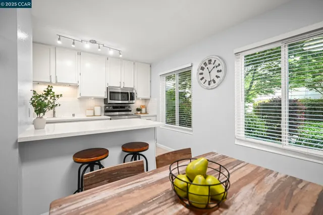 a kitchen with stainless steel appliances a dining table chairs and window