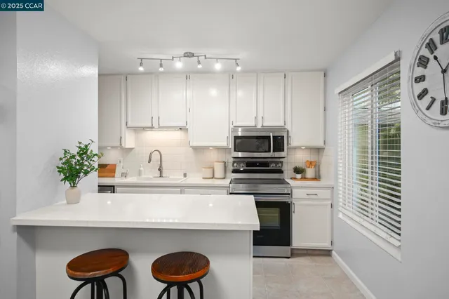 a kitchen with stainless steel appliances a white table chairs in it and white cabinets