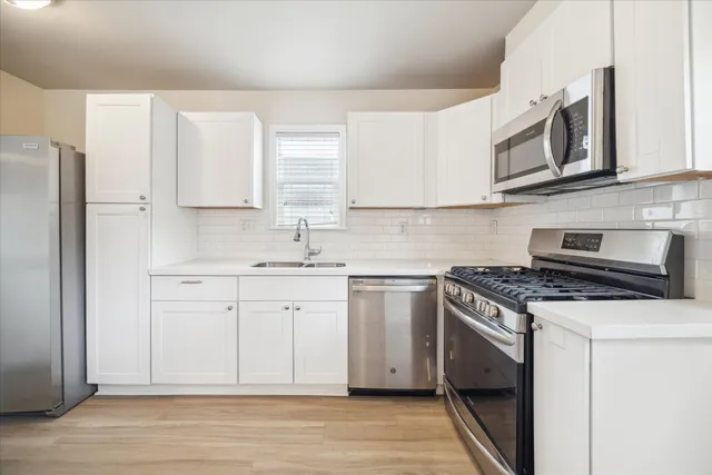 a kitchen with stainless steel appliances white cabinets and a stove top oven