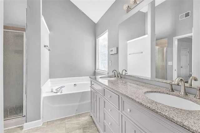 a bathroom with a granite countertop double vanity sink and mirror