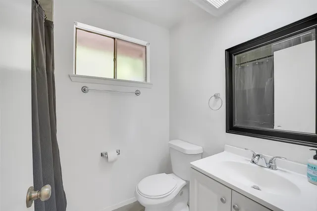 a bathroom with a toilet a sink a mirror and a window