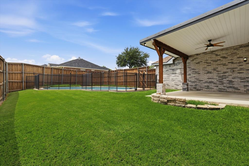 4545 Ridgepointe Drive The Colony, TX 75056 - Photo 11 of 37 Expansive backyard featuring a covered patio with a ceiling fan, brick exterior, and a fenced swimming pool