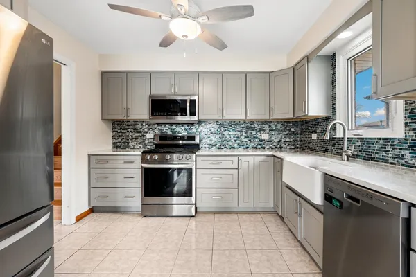 a kitchen with stainless steel appliances granite countertop a stove top oven a sink and a refrigerator