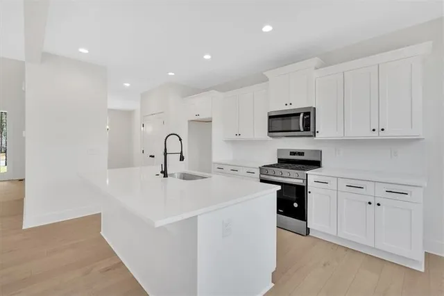 a kitchen with stainless steel appliances granite countertop a sink and white cabinets
