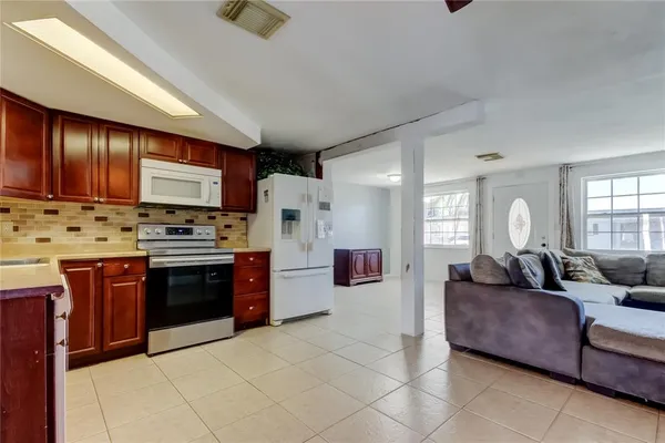 a large living room with stainless steel appliances granite countertop a couch and a view of kitchen
