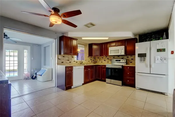 a kitchen with a refrigerator a stove top oven a sink dishwasher and white cabinets with wooden floor