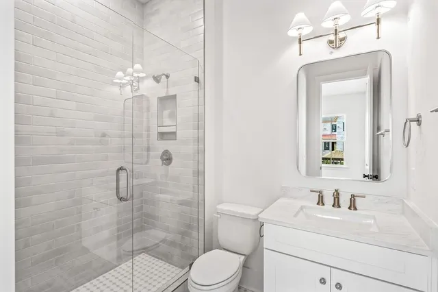 a bathroom with a toilet sink vanity granite and shower