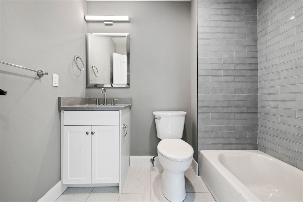 3 Burke Lane, Unit 203 Wellesley, MA 02481 - Photo 19 of 23 a bathroom with a toilet a sink a mirror and bathtub