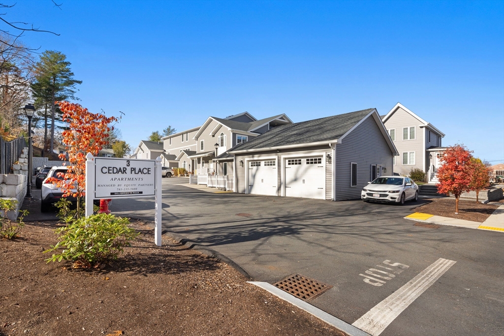 3 Burke Lane, Unit 203 Wellesley, MA 02481 - Photo 20 of 23 a front view of a house with a yard and garage