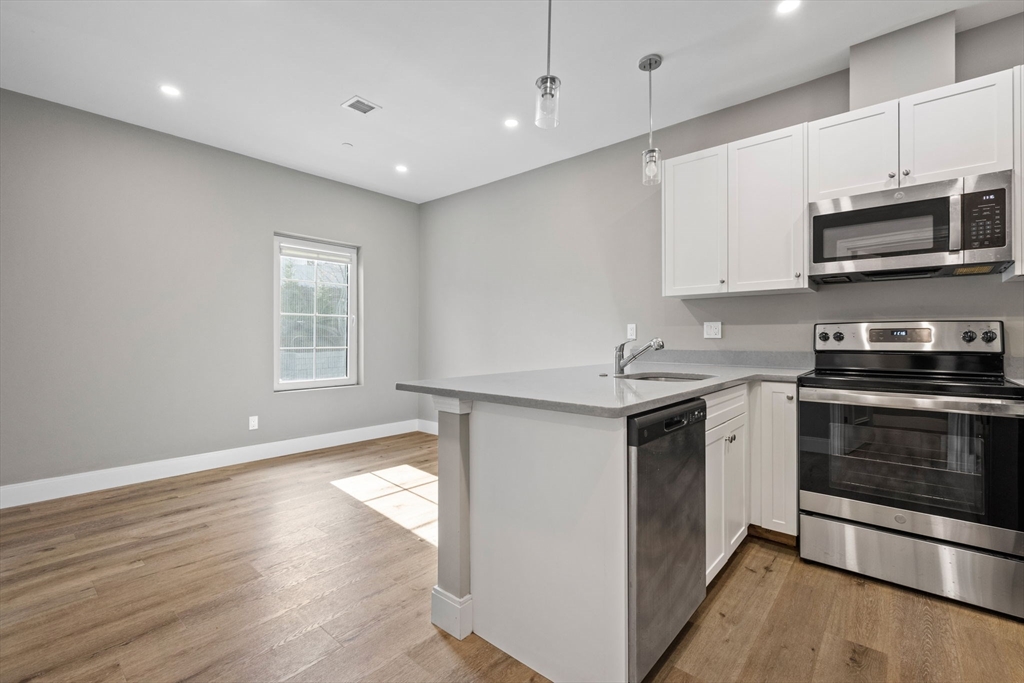 3 Burke Lane, Unit 203 Wellesley, MA 02481 - Photo 2 of 23 a kitchen with stainless steel appliances granite countertop a stove a sink and a microwave