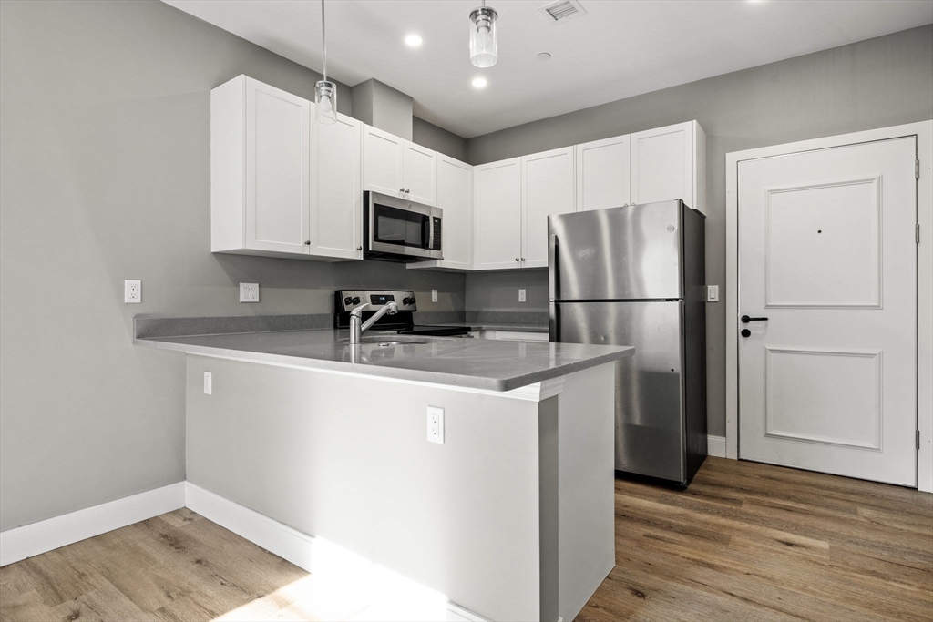 3 Burke Lane, Unit 203 Wellesley, MA 02481 - Photo 4 of 23 a kitchen with a refrigerator a microwave a sink and cabinets