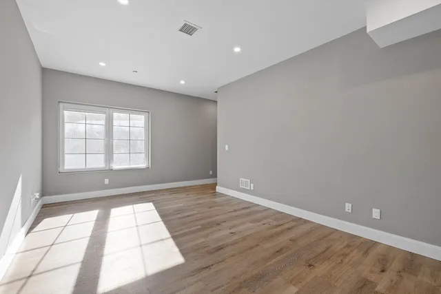 an empty room with wooden floor and windows