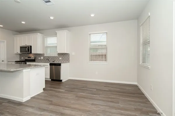a kitchen with granite countertop a stove top oven a sink a window and white cabinets
