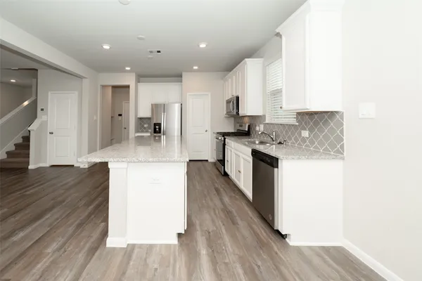 a kitchen with a sink microwave and wooden floor