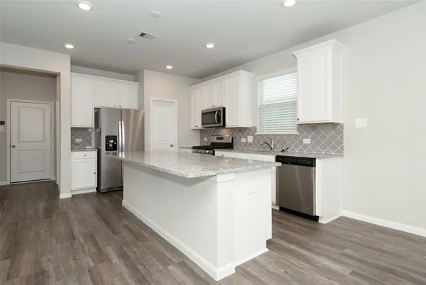 a kitchen with granite countertop a refrigerator and a stove top oven