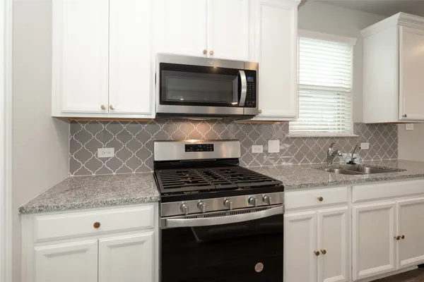 a kitchen with granite countertop white cabinets and appliances