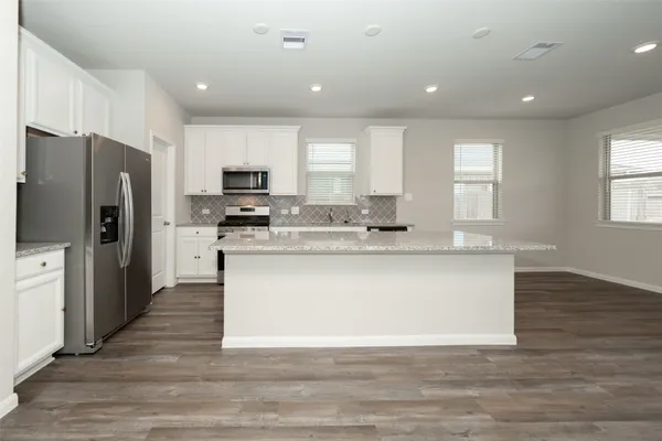 a large kitchen with stainless steel appliances granite countertop a stove a sink and a refrigerator