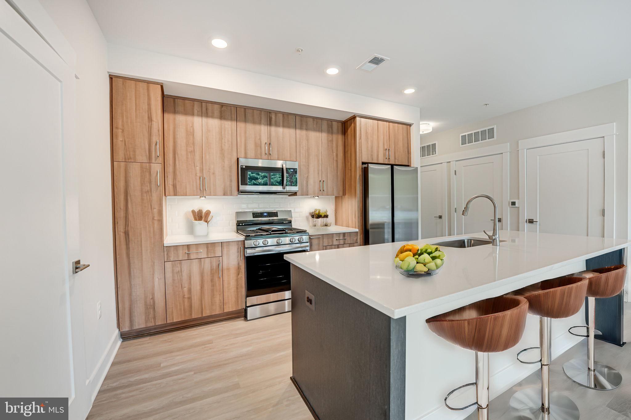43795 Transit Square, Unit 101 Ashburn, VA 20147 - Photo 15 of 35 a kitchen with stainless steel appliances granite countertop a refrigerator a sink dishwasher and a stove with wooden floor