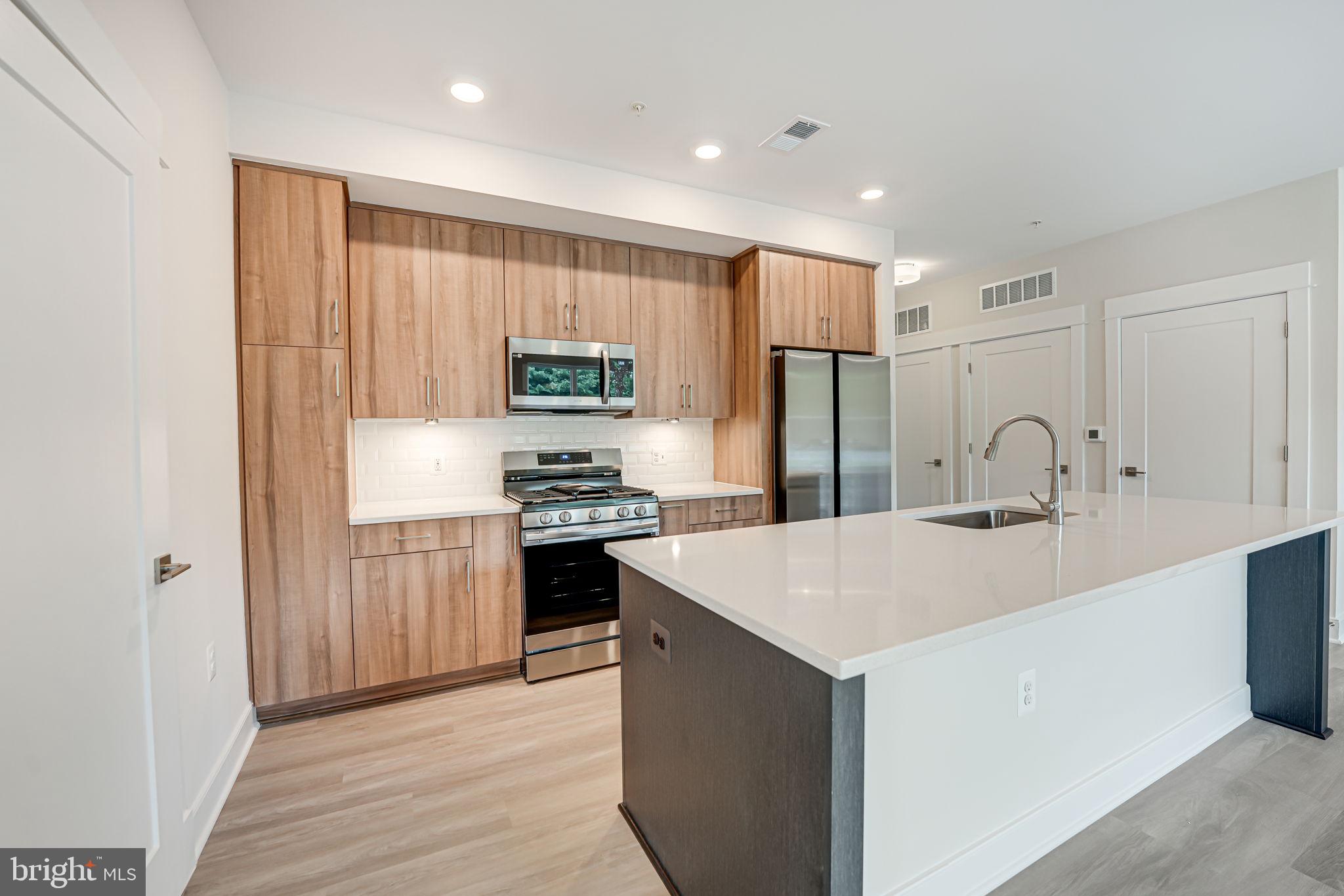 43795 Transit Square, Unit 101 Ashburn, VA 20147 - Photo 16 of 35 a kitchen with kitchen island a sink stainless steel appliances and refrigerator
