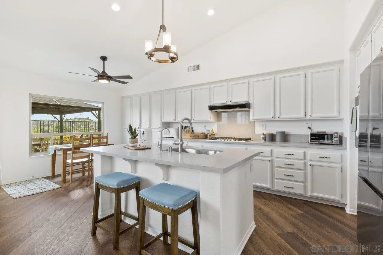 5167 Avenida De La Plata Oceanside, CA 92057 - Photo 14 of 53 a kitchen with stainless steel appliances kitchen island granite countertop a table chairs sink and cabinets
