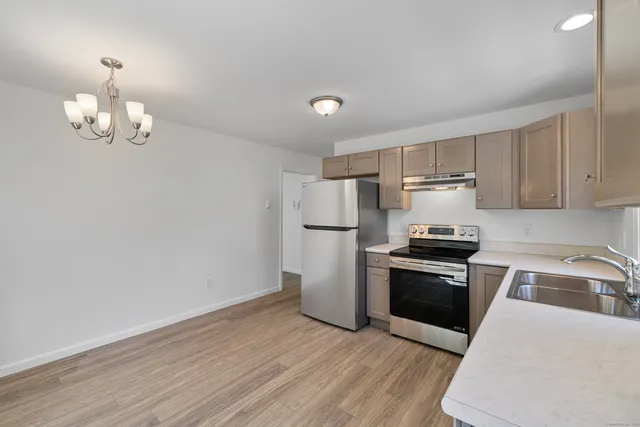 a kitchen with granite countertop stainless steel appliances a stove top oven a sink and cabinets