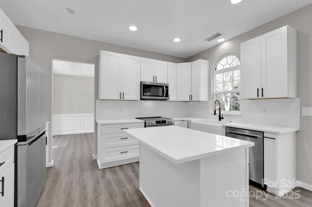 a kitchen with a sink a stove a microwave a center island and cabinets