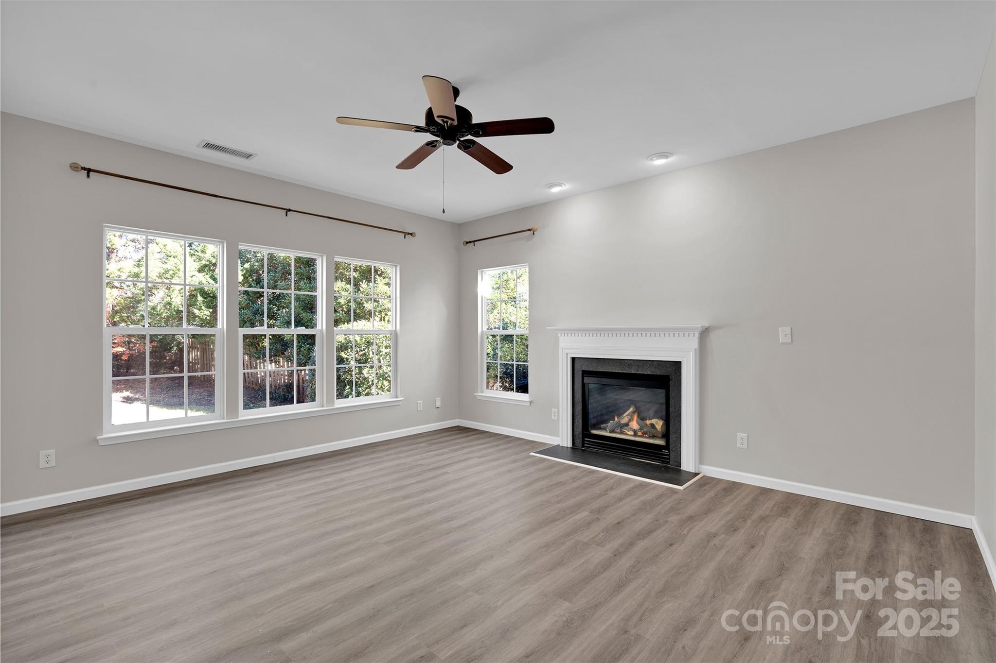 9211 Hickory Tree Lane Charlotte, NC 28277 - Photo 21 of 46 a view of an empty room with wooden floor fireplace and a window