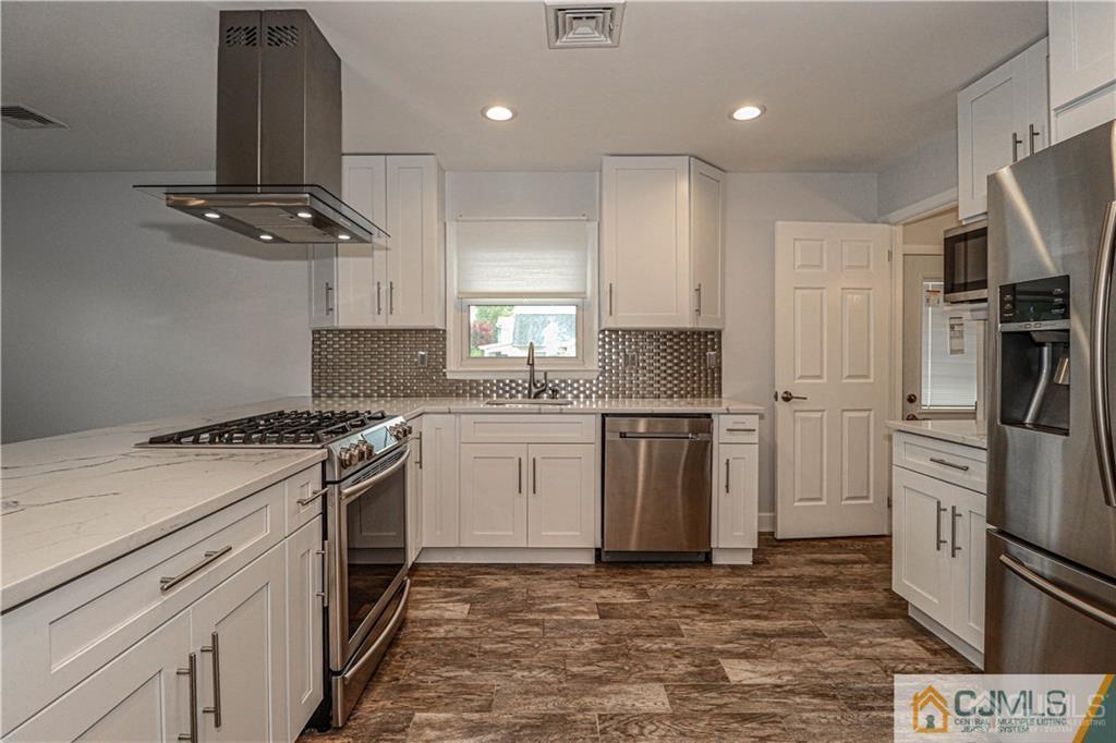 578 Chain O' Hills Road Colonia, NJ 07067 - Photo 5 of 39 a kitchen with white cabinets and stainless steel appliances