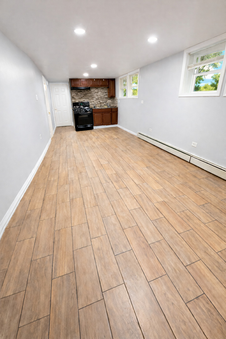 5518 West Melrose Street, Unit G Chicago, IL 60641 - Photo 3 of 8 an empty room with kitchen view and windows