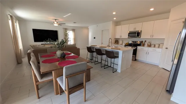 a kitchen with a dining table chairs and refrigerator