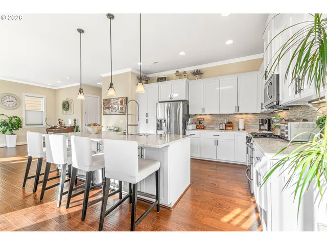 a kitchen with stainless steel appliances kitchen island granite countertop a table chairs and a view of living room