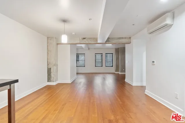 a view of kitchen and empty room with wooden floor
