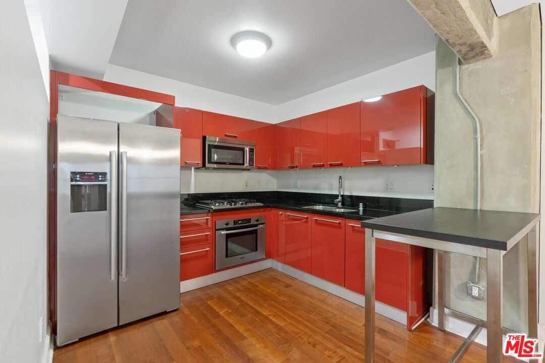 416 South Spring Street, Unit 210 Los Angeles, CA 90013 - Photo 9 of 18 a kitchen with stainless steel appliances granite countertop a refrigerator and a sink
