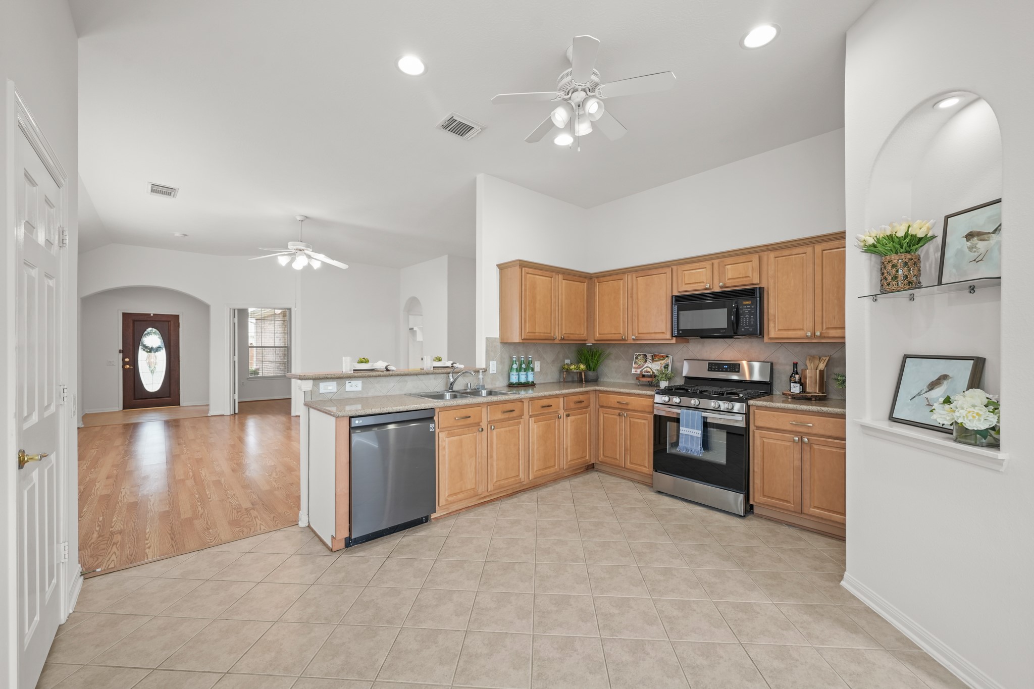 25003 Spring Ash Lane Katy, TX 77494 - Photo 14 of 43 This inviting kitchen boasts tile floors, recessed lighting and a lighted ceiling fan, centered around a stunning silestone breakfast bar with a dual-basin stainless steel sink integrated into countertops.