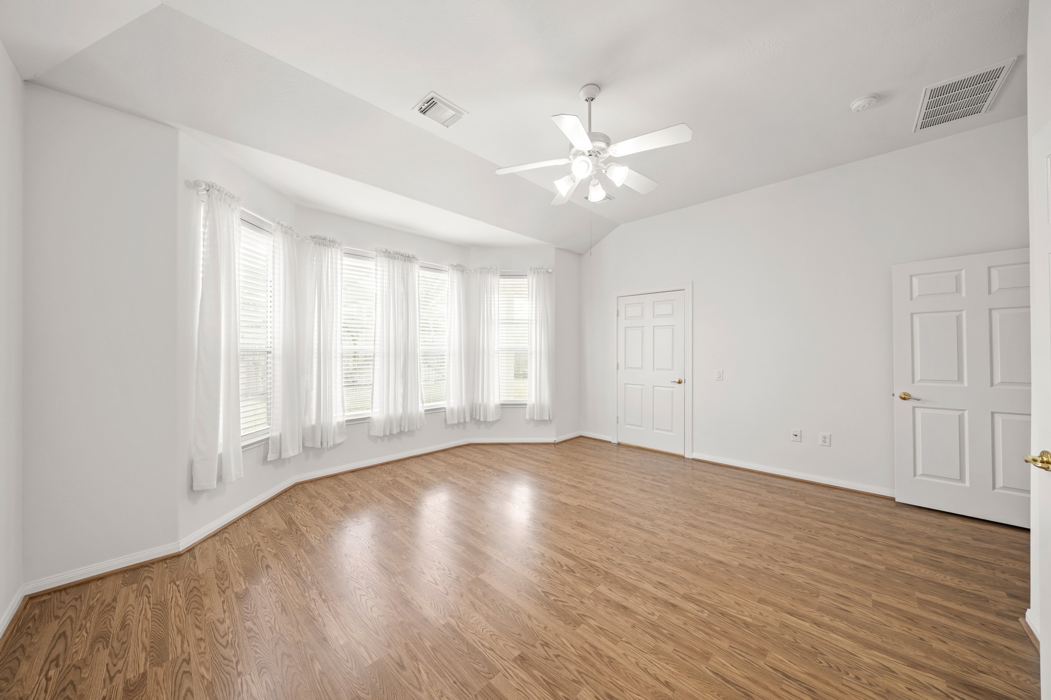 25003 Spring Ash Lane Katy, TX 77494 - Photo 19 of 43 The primary suite exudes relaxation, featuring a tranquil space complemented by tall ceilings with a ceiling fan and integrated light, and a spacious walk-in closet to the right. The drapes stay with the home.