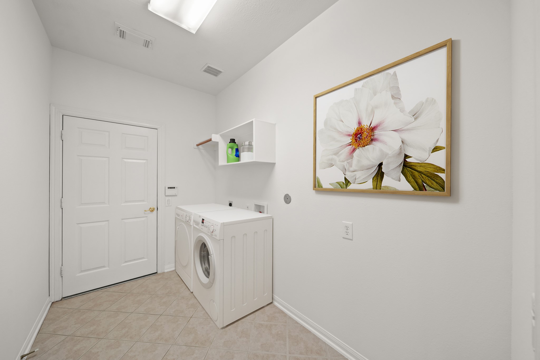 25003 Spring Ash Lane Katy, TX 77494 - Photo 32 of 43 Discover everyday convenience in this utility room, featuring sleek tile floors, a handy storage shelf, a hanging rod and an electric dryer hookup. Access to the two car garage with wheel chair ramp is just through the doorway. The home also has a whole home water softener system!This picture has been virtually staged.