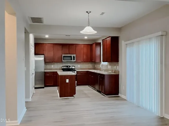 a large kitchen with stainless steel appliances granite countertop wooden cabinets a stove a sink and a refrigerator