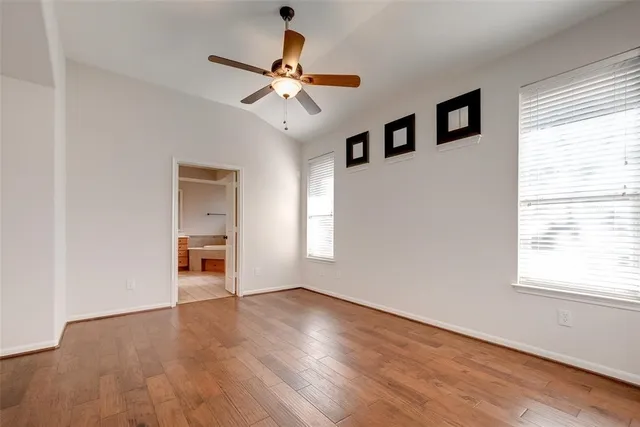 a view of an empty room with a window and wooden floor