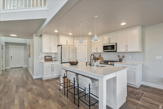 882 Spring Dew Lane Lehi, UT 84048 - Photo 12 of 46 Kitchen featuring white cabinetry, a kitchen breakfast bar, hanging light fixtures, and white appliances