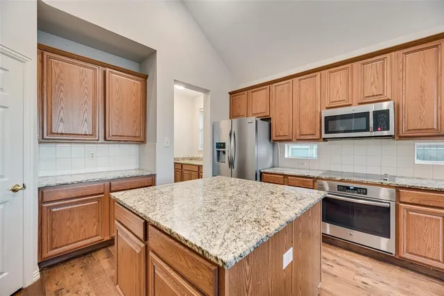 a kitchen with stainless steel appliances granite countertop a stove microwave and refrigerator