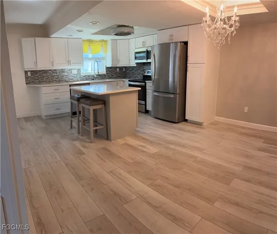 a kitchen with stainless steel appliances granite countertop a refrigerator a sink dishwasher a stove with wooden cabinets and floor