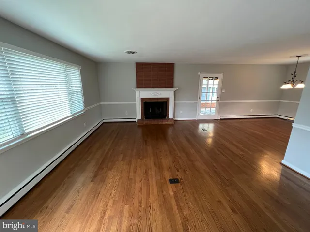 a view of a livingroom with wooden floor and a fireplace