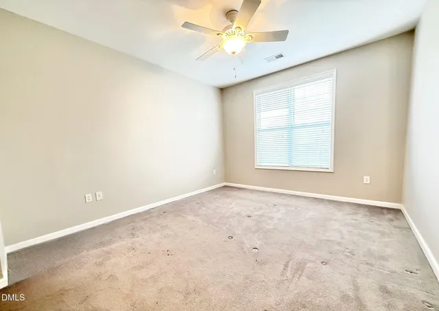 an empty room with a window and a fan