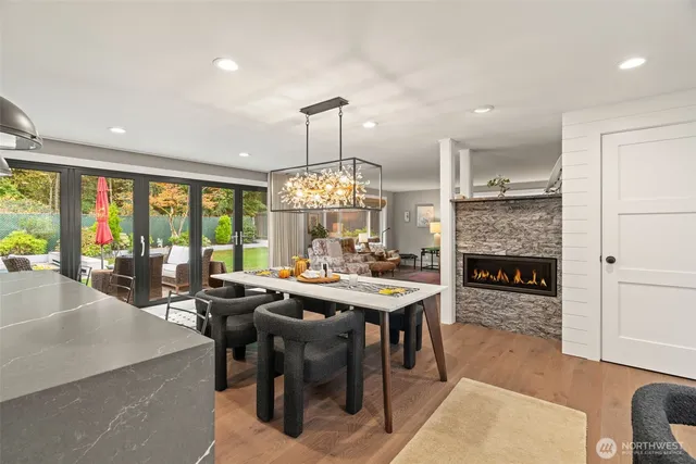 a view of a dining room and livingroom view with furniture wooden floor a rug a flat screen tv a rug and a chandelier