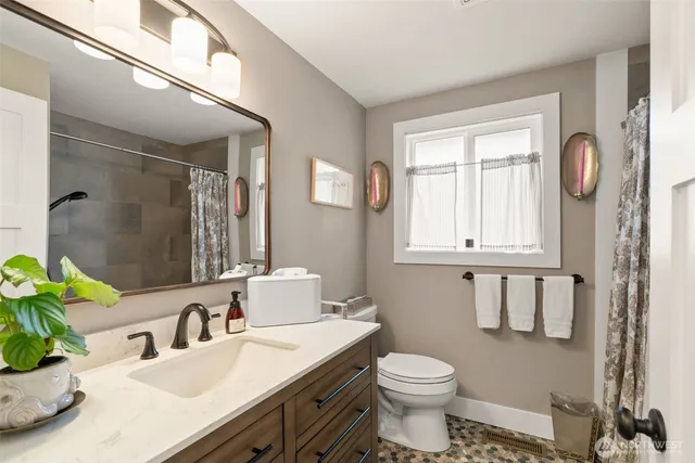 a bathroom with a granite countertop sink mirror vanity and toilet